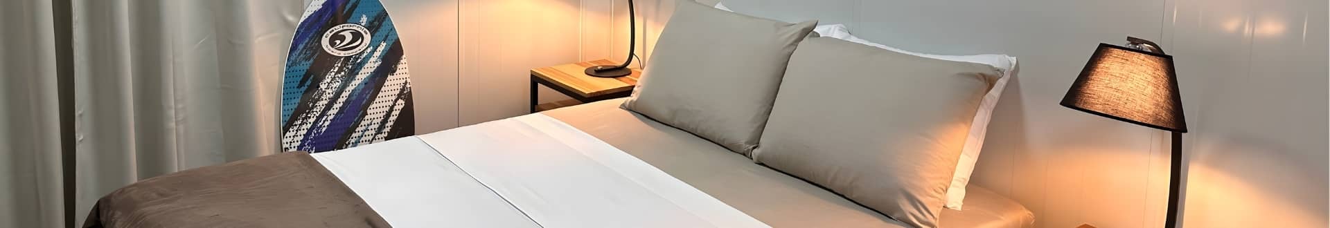 Cozy bungalow bedroom with surfboard and warm lighting at Vivirí Beach Bungalows, Costa Rica